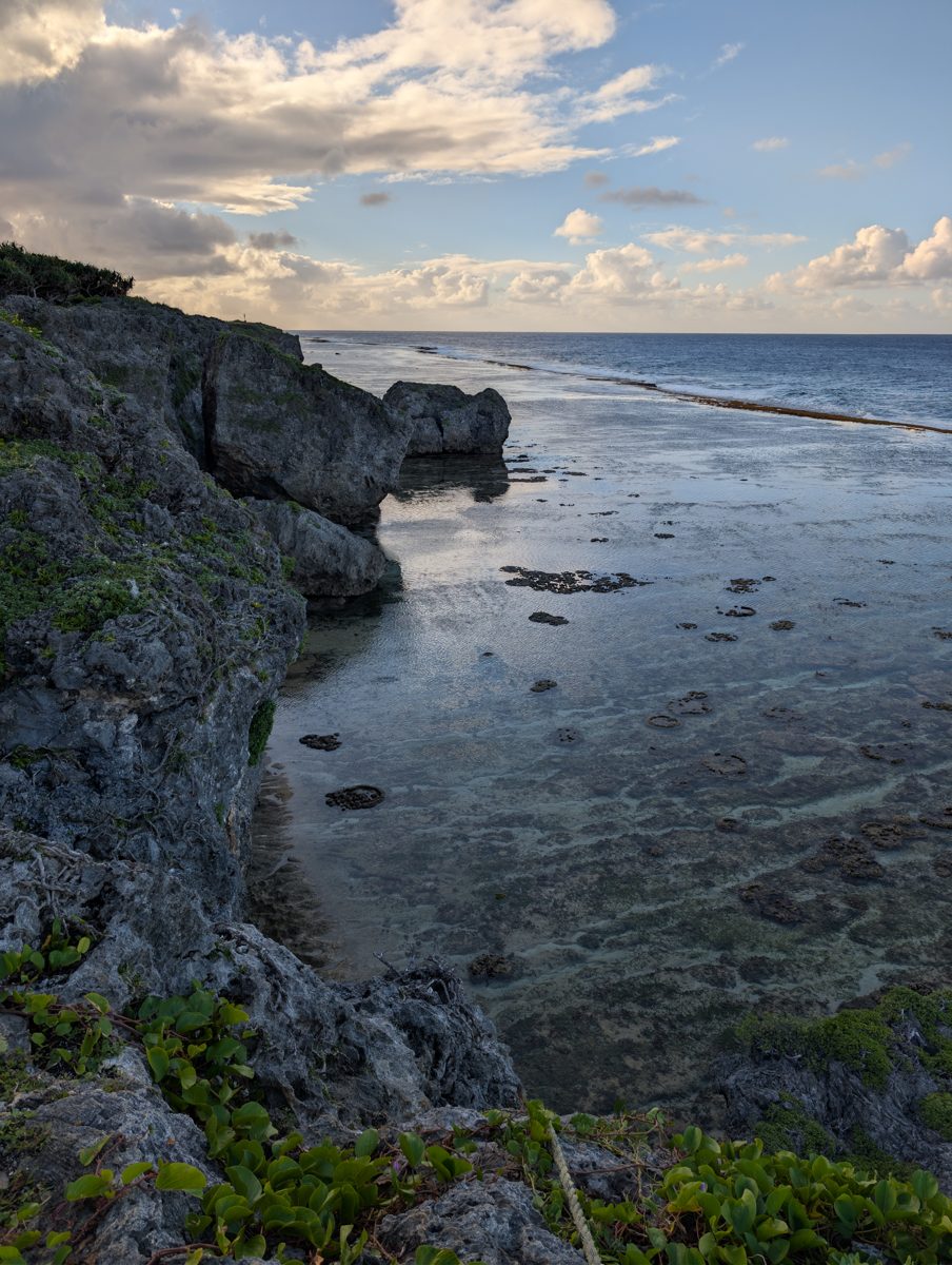 Elevated view from rough coastal limestone across a narrow cove and shallow reef flat toward the open ocean at HS112.