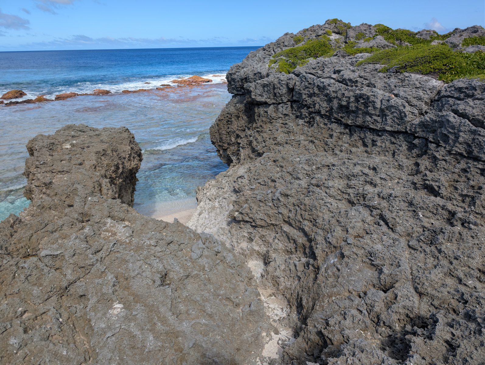 South-coast reddish outcrop: The lower south-coast Mitiaro outcrop is reddish and fades upward without a sharp top; weathering or preservation cause remains uncertain.